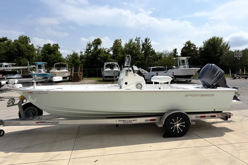 Slide: The Image of 2013 Sportsman Masters 207 Bay Boat on trailer, parked outdoors with other boats. - 4