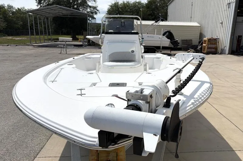 Slide: The Image of 2013 Sportsman Masters 207 Bay Boat with trolling motor, parked outdoors near a warehouse. - 9