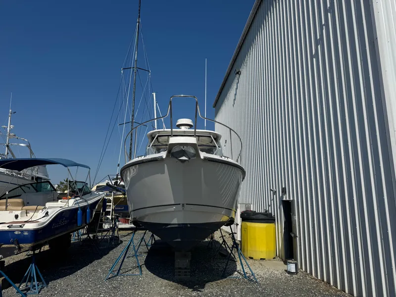 Slide: The Image of 2006 Boston Whaler 305 Conquest boat propped beside storage building. - 2