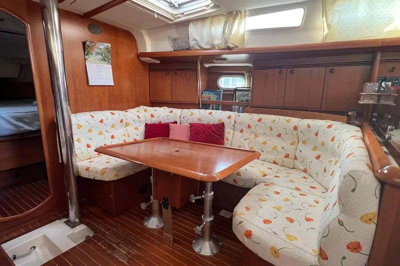 Slide: The Image of Cozy interior of 2004 Jeanneau Sun Odyssey 40 sailboat with floral-patterned seating and wooden table. - 2