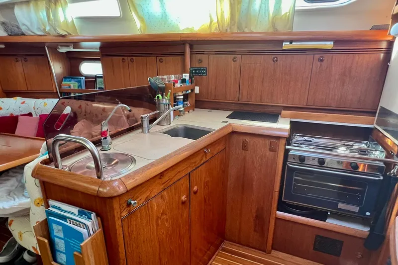 Slide: The Image of Interior of 2004 Jeanneau Sun Odyssey 40 yacht, featuring a compact wooden kitchen galley. - 7