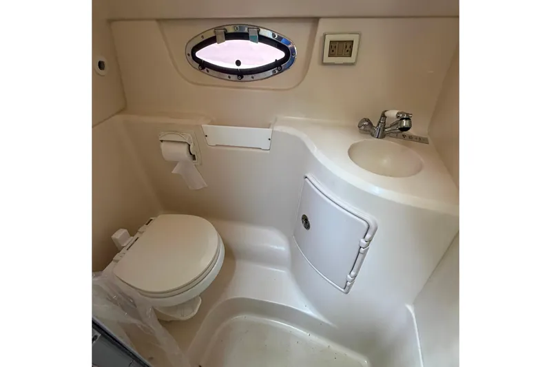 Slide: The Image of Compact bathroom in 2008 Regal 2565 Window Express boat with toilet, sink, and porthole. - 21