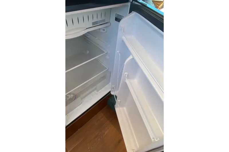 Slide: The Image of Open refrigerator inside 1986 Ocean Yachts 48 Super Sport, showing empty shelves and door compartments. - 10