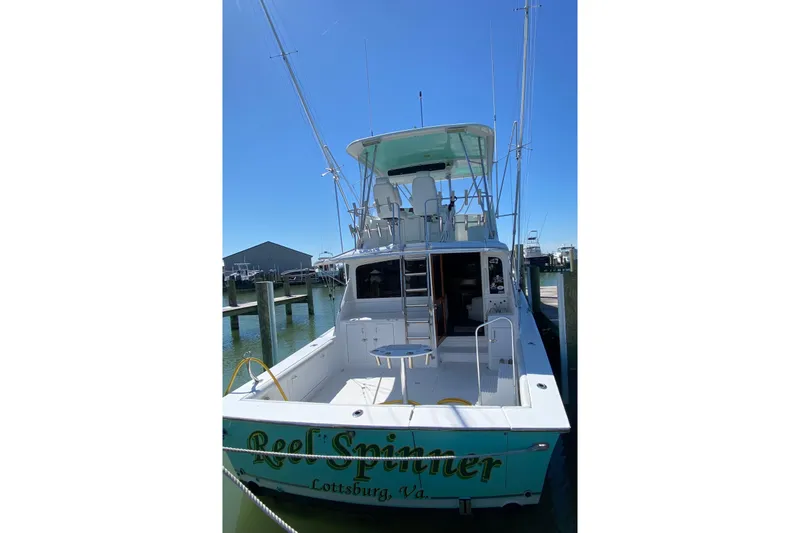 Slide: The Image of 1986 Ocean Yachts 48 Super Sport docked, rear view with fishing equipment, clear sky. - 3
