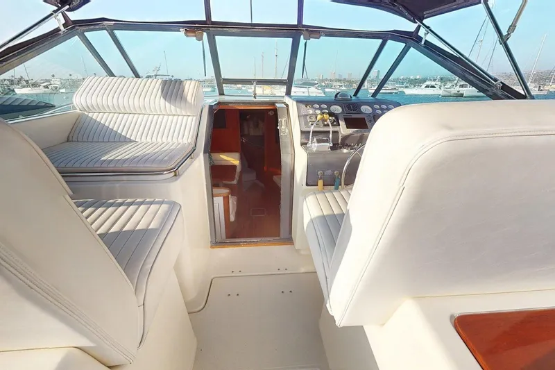 The Image of Interior view of 1989 Tiara 3300 Open yacht cockpit with white seating and control panel. - 1