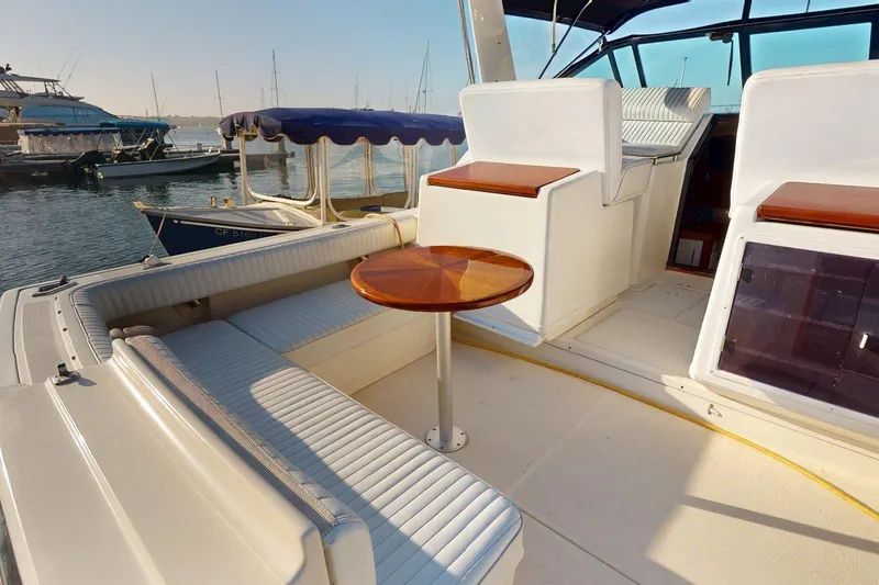 Slide: The Image of 1989 Tiara 3300 Open yacht interior with seating and wooden table, docked at marina. - 12