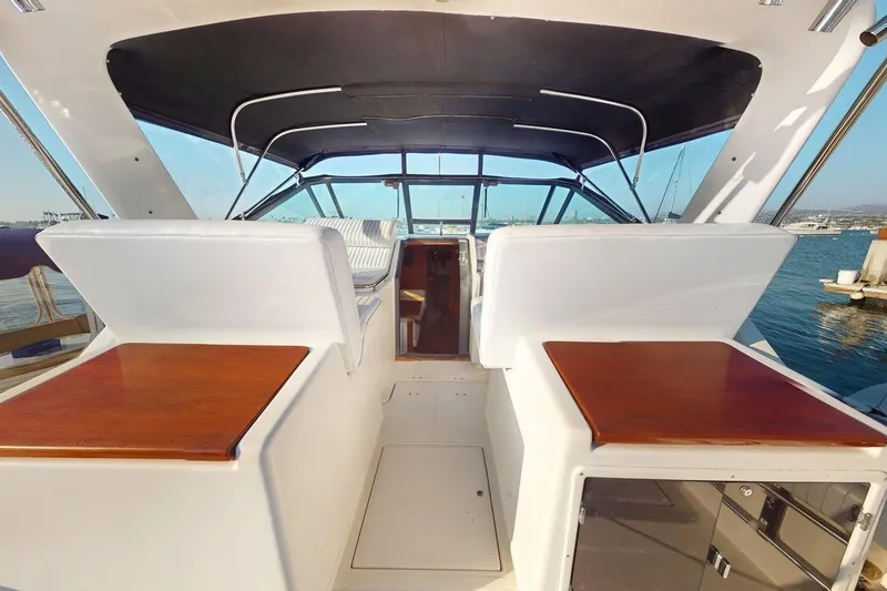 Slide: The Image of 1989 Tiara 3300 Open yacht interior with seating and wooden tables, docked at marina. - 16