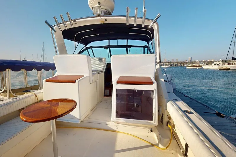 Slide: The Image of 1989 Tiara 3300 Open yacht interior with seating and table, docked by the water. - 27