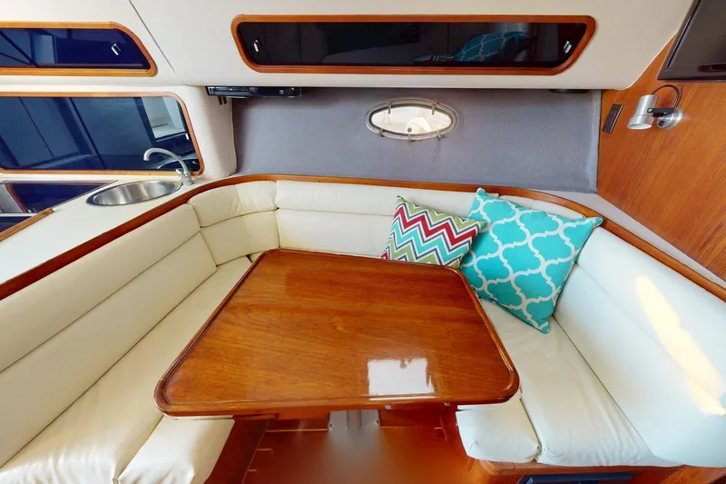 Slide: The Image of 1989 Tiara 3300 Open yacht interior with cozy seating, wooden table, and colorful cushions. - 3