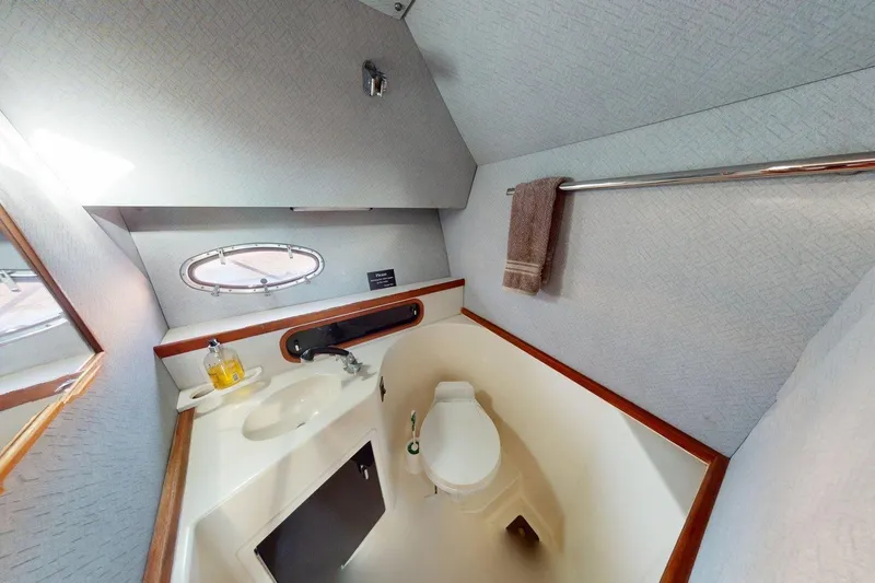 Slide: The Image of 1989 Tiara 3300 Open yacht bathroom with sink, toilet, and porthole window. - 9