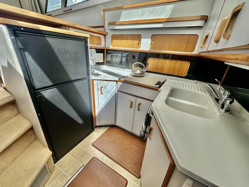 Slide: The Image of Interior of 1990 Sea Ray 380 Aft Cabin yacht, featuring kitchen with sink and refrigerator. - 4