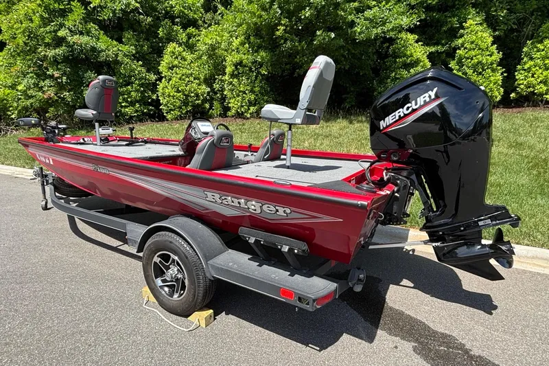 Slide: The Image of 2024 Ranger RT188 boat with Mercury engine, parked on a trailer, surrounded by greenery. - 14