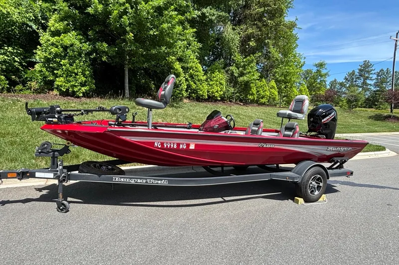 Slide: The Image of 2024 Ranger RT188 boat on trailer, red color, parked outdoors on sunny day. - 2