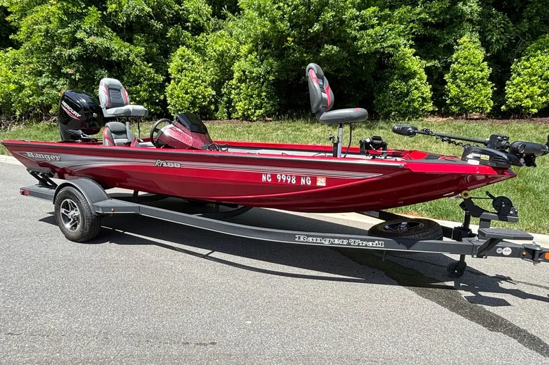 Slide: The Image of 2024 Ranger RT188 boat in red on a trailer, parked outdoors. - 3