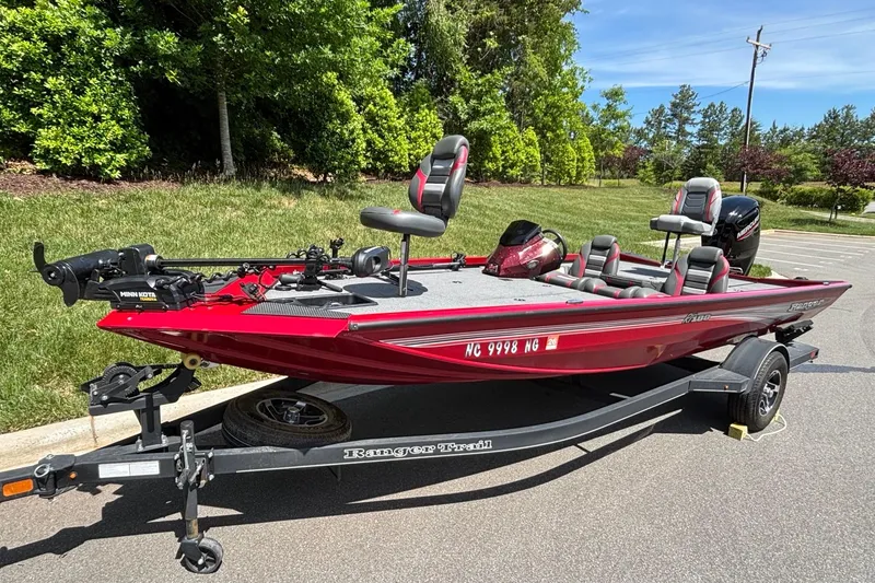 Slide: The Image of 2024 Ranger RT188 red fishing boat on trailer, parked outdoors with lush greenery background. - 4