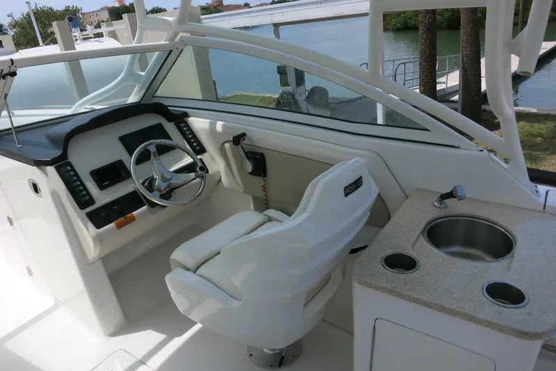 Slide: The Image of 2018 Robalo R247 Dual Console boat interior with helm, steering wheel, and sink. - 12