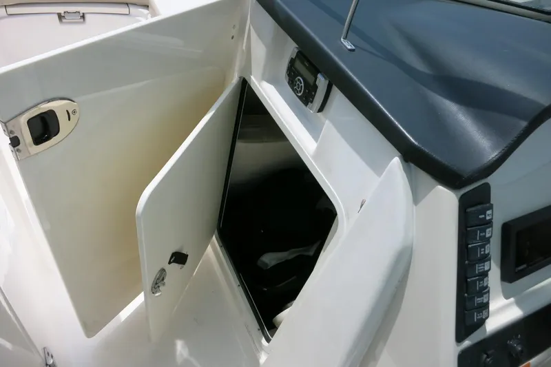 Slide: The Image of 2018 Robalo R247 Dual Console boat storage compartment with open door and control panel. - 21