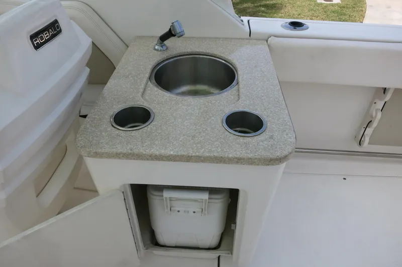 Slide: The Image of 2018 Robalo R247 Dual Console boat sink with faucet and storage compartment. - 22