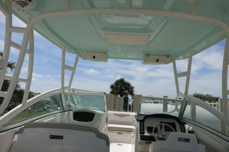 Slide: The Image of 2018 Robalo R247 Dual Console boat interior with helm and seating under a blue sky. - 23