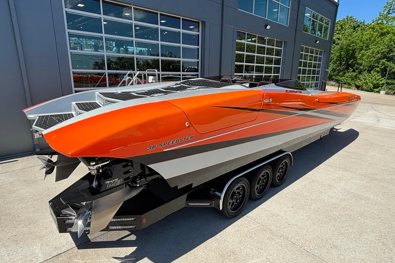 Slide: The Image of 2020 Eliminator 36 Daytona Coupe boat with vibrant orange and silver design, parked outdoors. - 8