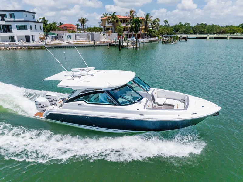 Slide: The Image of 2020 Tiara Yachts 34lx cruising on water near modern homes. - 2