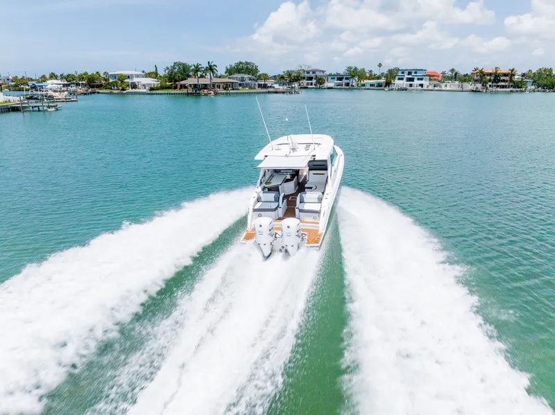 Slide: The Image of Tiara Yachts 34lx 2020 cruising fast on water, coastal homes in background. - 3