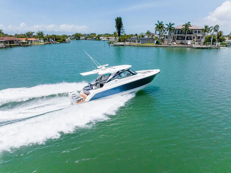 Slide: The Image of 2020 Tiara Yachts 34lx cruising on water, surrounded by houses and palm trees. - 5