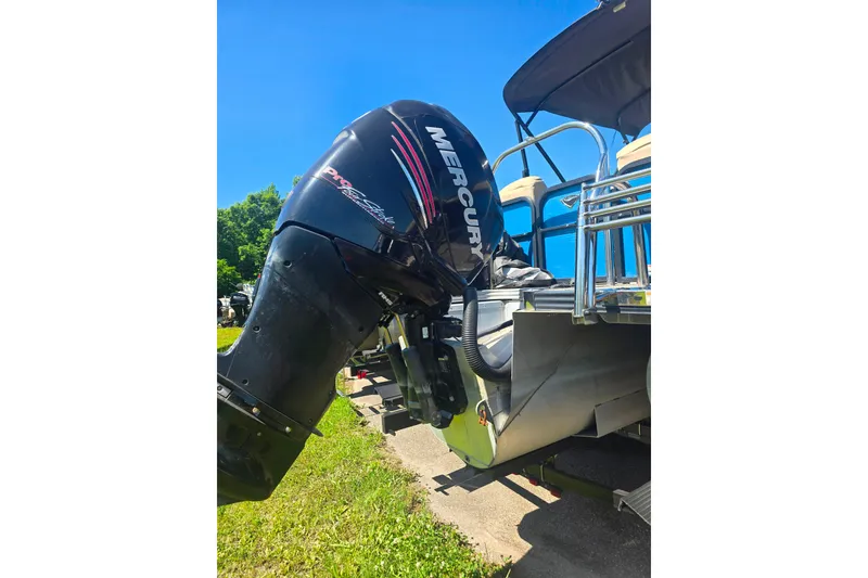 Slide: The Image of 2018 Manitou 23 Encore SL boat with Mercury outboard motor, parked on grass. - 12