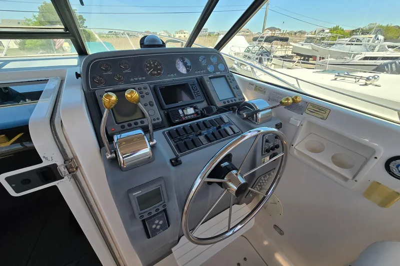 Slide: The Image of 1999 Tiara Yachts 3100 Open helm with steering wheel and control panel. - 13