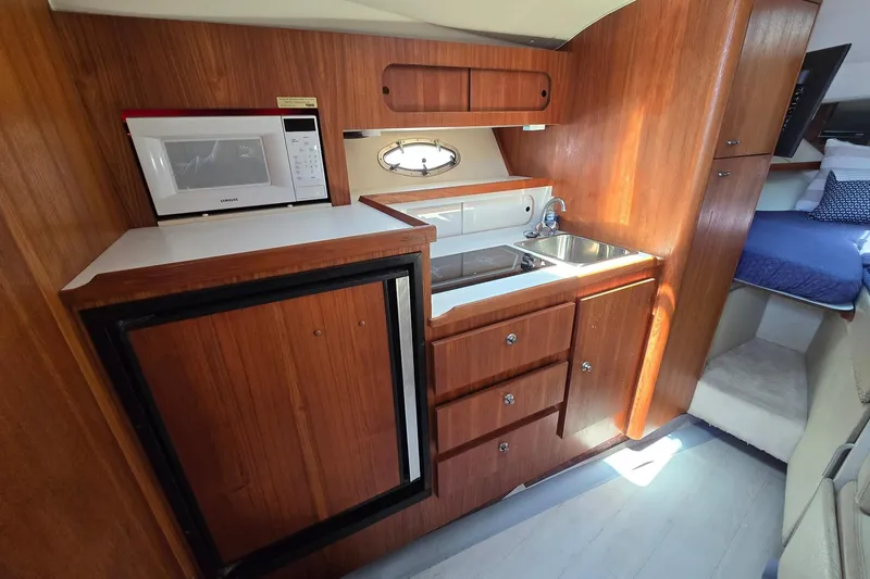 Slide: The Image of 1999 Tiara Yachts 3100 Open interior kitchen with wood cabinetry, microwave, and sink. - 16