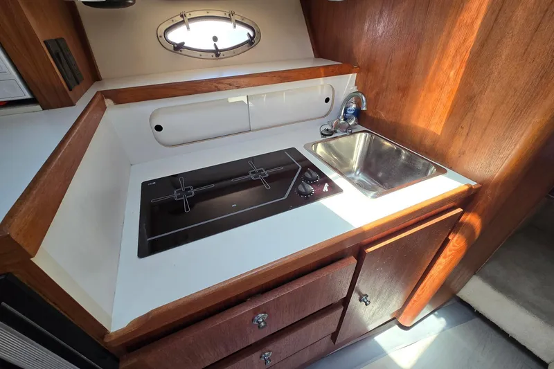Slide: The Image of Compact kitchen area in a 1999 Tiara Yachts 3100 Open, featuring a stove and sink. - 17