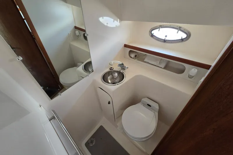 Slide: The Image of 1999 Tiara Yachts 3100 Open bathroom with sink, toilet, and porthole window. - 19