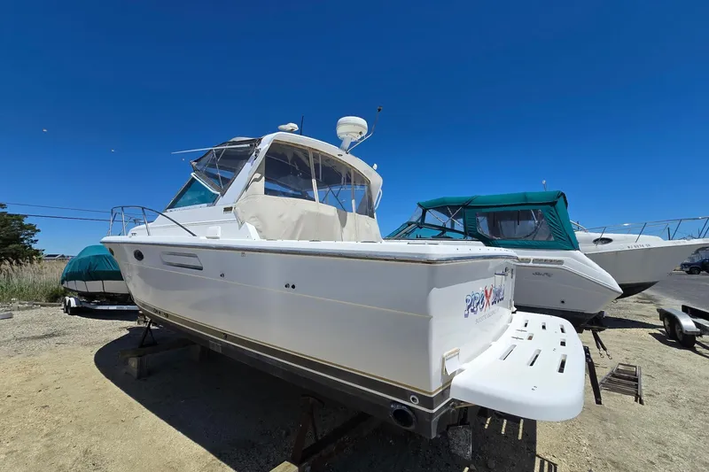Slide: The Image of 1999 Tiara Yachts 3100 Open boat on dry dock under clear blue sky. - 3