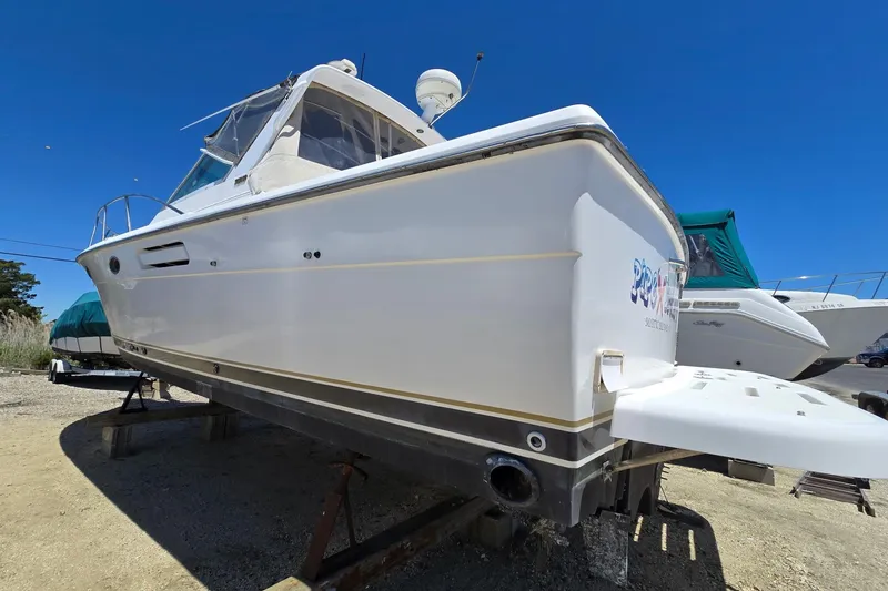Slide: The Image of 1999 Tiara Yachts 3100 Open boat on dry dock under clear blue sky. - 4
