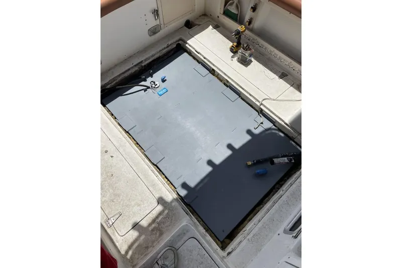 Slide: The Image of Open hatch on 1995 Mako 293 Walk Around boat, showing interior components and tools. - 14