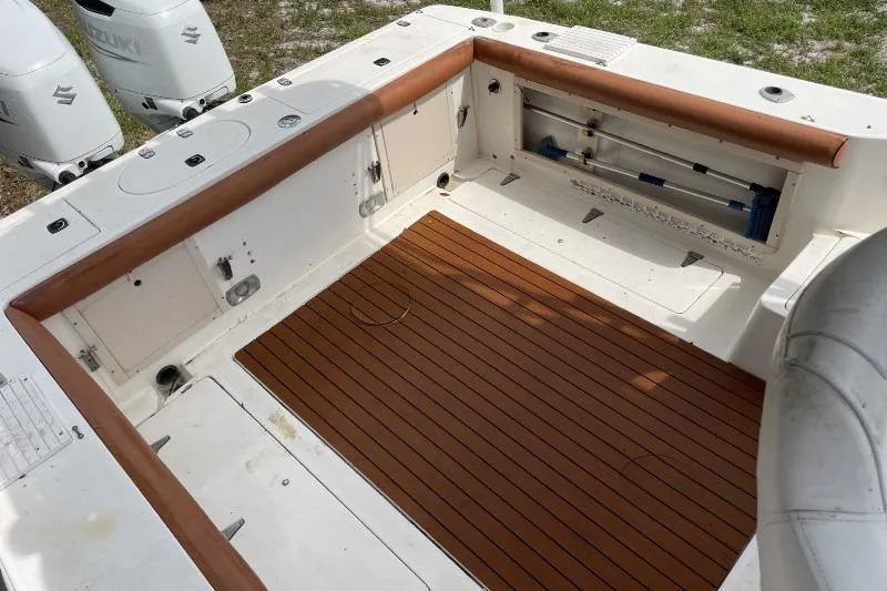 Slide: The Image of 1995 Mako 293 Walk Around boat deck with wood flooring and storage compartments. - 10