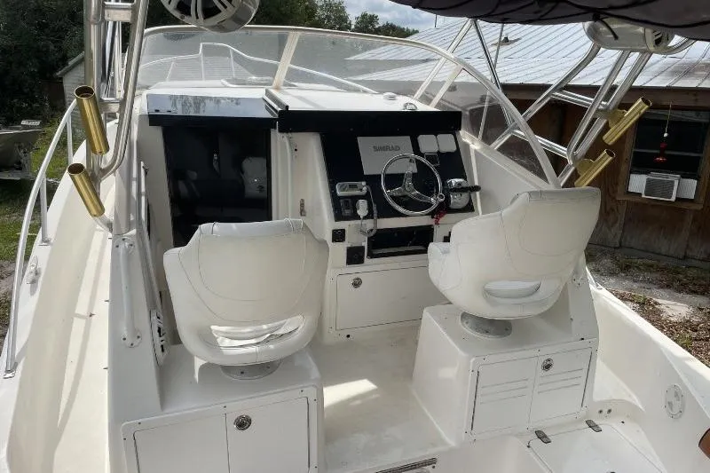 Slide: The Image of 1995 Mako 293 Walk Around boat cockpit with dual white seats and steering console. - 4