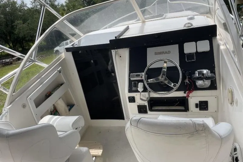 Slide: The Image of 1995 Mako 293 Walk Around boat cockpit with steering wheel and navigation equipment. - 5
