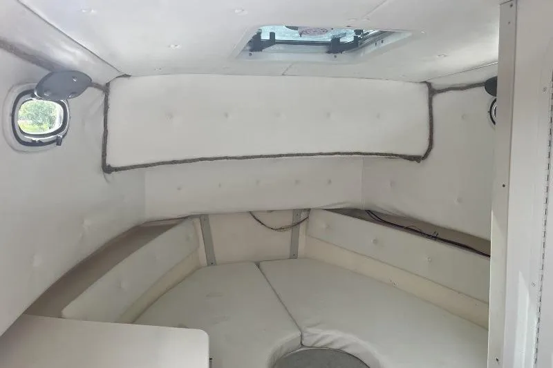 Slide: The Image of 1995 Mako 293 Walk Around cabin interior with white cushioned seating and porthole windows. - 6