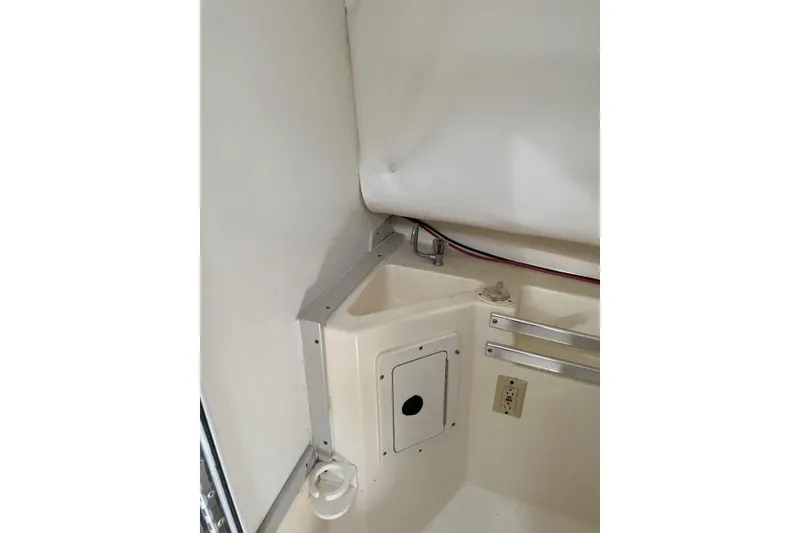 Slide: The Image of Interior corner of a 1995 Mako 293 Walk Around boat, featuring storage and wiring. - 7