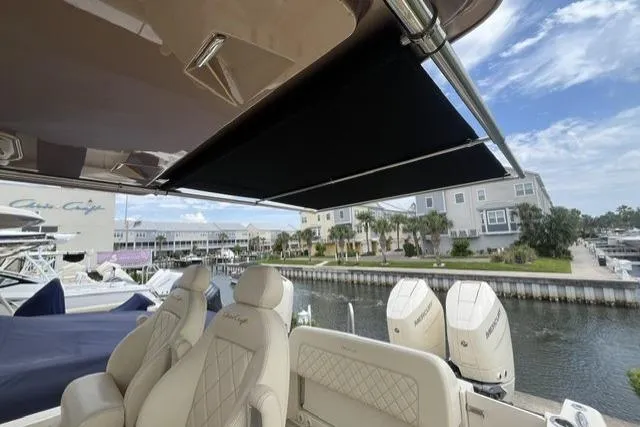 Slide: The Image of 2024 Chris-Craft Catalina 30 boat with luxurious seating and retractable sunshade at a marina. - 4
