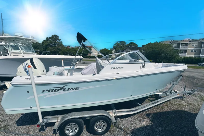 Slide: The Image of 2016 PROLINE 23DC boat on trailer under bright blue sky. - 18