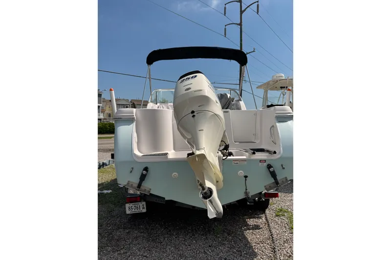 Slide: The Image of 2016 PROLINE 23DC boat with outboard motor, parked on gravel under clear sky. - 2