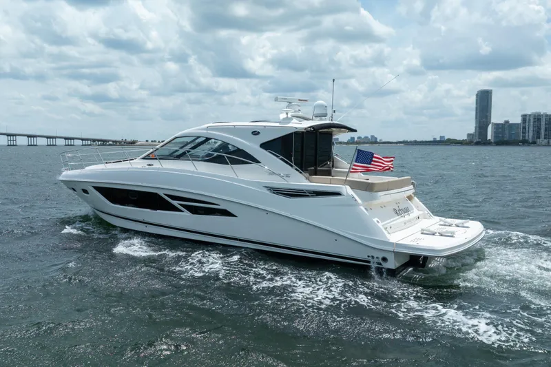 Slide: The Image of 2017 Sea Ray Sundancer 510 yacht cruising on open water with city skyline backdrop. - 4
