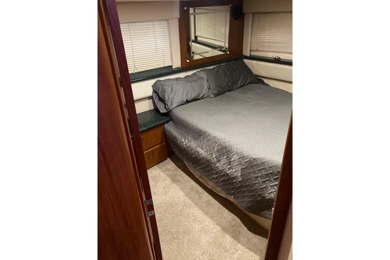 Slide: The Image of Cozy bedroom interior of 2001 Carver 356 Motor Yacht with gray bedding and wood accents. - 10