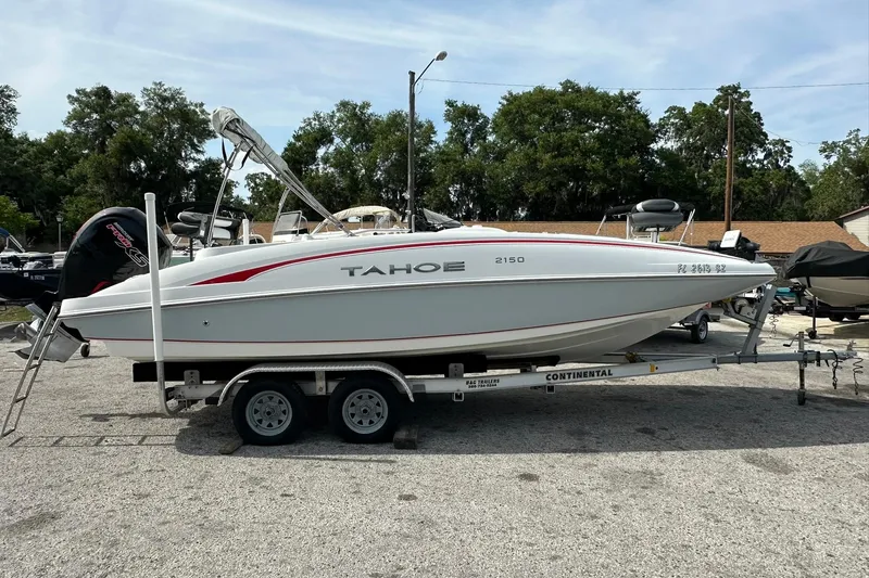 The Image of 2021 Tahoe 2150 boat on trailer, parked outdoors with trees in the background. - 1