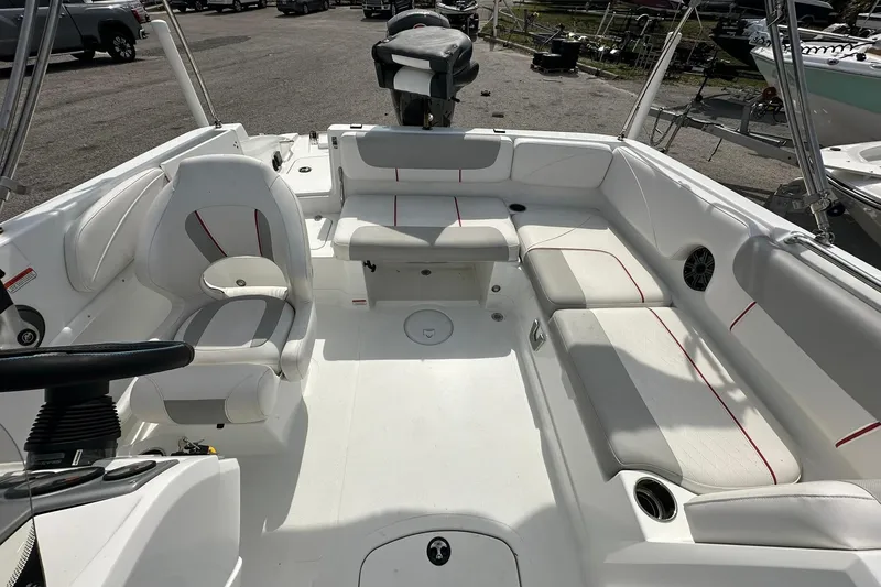 Slide: The Image of 2021 Tahoe 2150 boat interior with white seating and red accents, parked outdoors. - 15