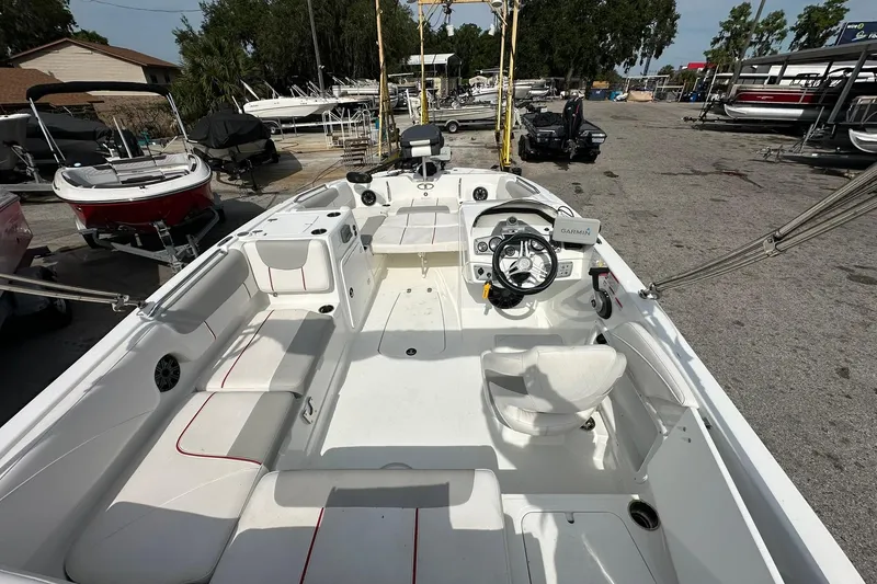 Slide: The Image of 2021 Tahoe 2150 boat interior with steering wheel and seating, parked in a marina. - 23