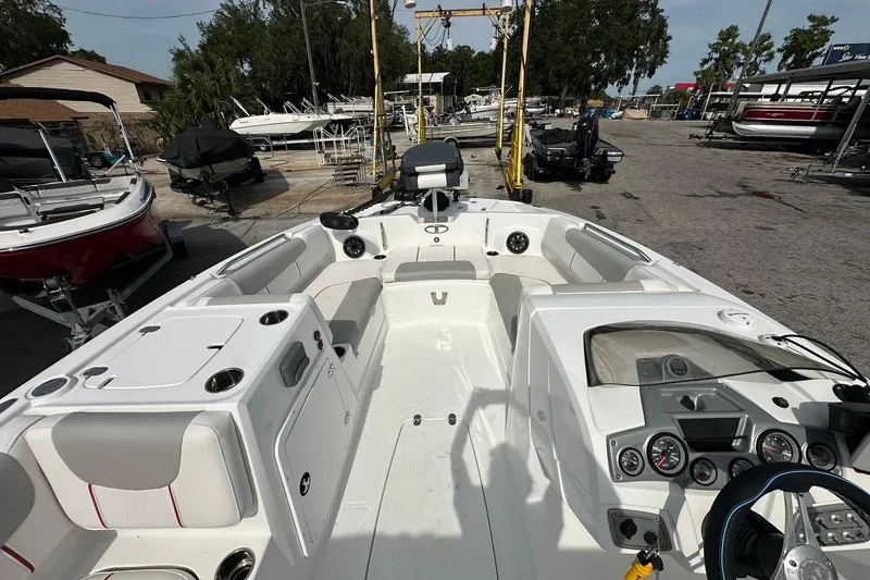 Slide: The Image of 2021 Tahoe 2150 boat interior with seating and control panel, parked in a marina. - 24