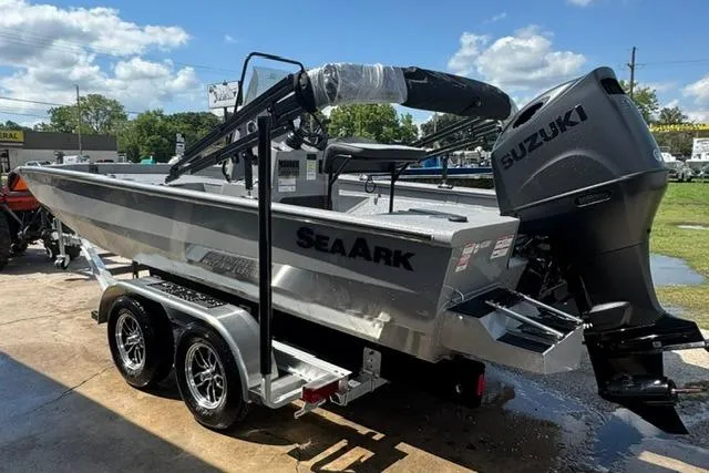 The Image of 2026 SeaArk Bay Runner 210 boat with Suzuki engine on a trailer, outdoors. - 0